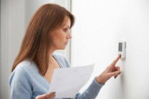 Woman Adjusting HVAC Thermostat In Recovery Mode